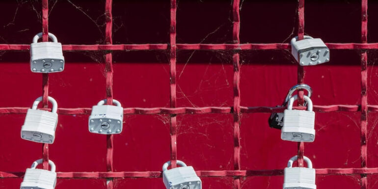 A red gate with white padlocks on it.